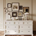 White Entryway Cabinet and Sideboard With Multiple Drawers Decorative Vase Statue Lamp and Framed Artworks