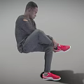 Man wearing gray long sleeve and gray pants lifting one leg to adjust red sneakers