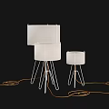 Modern Floor Lamps With Light Colored Shades And Metal Tripod Stands On Black Background