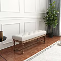 White Tufted Bench with Wooden Legs in Room with White Paneled Walls and Green Plant