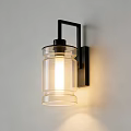 Contemporary Wall Sconce with Illuminated Clear Glass Shade and Black Metal Bracket on White Wall