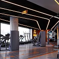 Modern Fitness Gym Interior Featuring Treadmills Ellipticals Strength Machines And Orange Accent Lighting