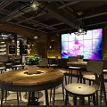Modern Industrial Bar Interior With Large LED Screen Brick Wall Wine Rack And Round Tables