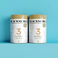 Blackmores Toddler Formula Stage 3 In White Cans With Gold Lids On Blue Background