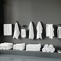 White Towels Organized Hanging on Gray Wall and Stacked with Rolled Towels and Slippers on Shelf
