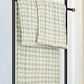 Black Metal Clothes Rack with Hanging Checkered Towels and Potted Plant