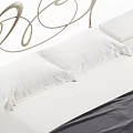 Elegant Double Bed With Curved Metal Headboard White Bedding Dark Blanket And Bedside Tables
