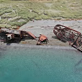 Aerial View Coastal Scenery Featuring Shipwreck Remains Sandy Beach Green Grass And Clear Blue Water