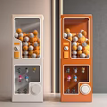 Two White And Orange Entertainment Vending Machines With Orange Gray Balls And Small Toys