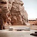 White Curved Irregular-Shaped Sofa In Rocky Cliff Setting With Central Fire Pit And Natural Surroundings