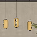 Three Japanese Yellow Lantern Pendant Lights with Japanese Characters on Light Wall and Green Plant