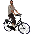 Man riding black bicycle with rear rack wearing gray shirt dark pants and white shoes