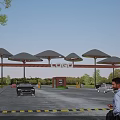 Modern Entrance Gate With Umbrella Shaped Canopies Logo Sign And Vehicles In Parking Area