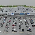 Aerial View of Large Retail Store Parking Lot Full of Cars and Green Surroundings