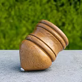 Tilted Wooden Top With Stacked Layers On Gray Tabletop And Green Plants In Background