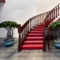 Elegant Spiral Staircase With Red Carpet Wooden Handrail And Green Plants Against White Walls