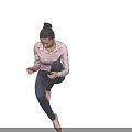 Woman In Pink Shirt And Blue Jeans Sitting Cross-Legged On Black Background With Ballet Shoes