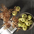 Green Apples in Bowl with Golden Leaves on Dark Tiles Background