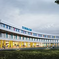 Modern School Building With Curved White Exterior Blue Accents Yellow Pillars And Glass Windows