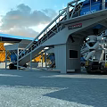 Industrial Factory Featuring Blue Roof Yellow Equipment Orange Construction Vehicles And White Blue Storage Silos