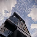 Modern High Rise Office Building with Glass Curtain Wall Surrounded by Trees Under Blue Sky