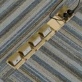 Golden Floor Socket Panel with Multiple Sockets Floor Mounted on Striped Carpet and Plug Inserted