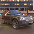 Black Range Rover SUV Parked On Urban Street With City Lights Reflection