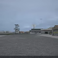 Industrial Factory With Open Space Surrounding Trees Gray Buildings Distant Tower Light Poles Overcast Sky