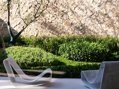 Outdoor Lounge Chairs With Modern Design Against Stone Wall And Green Bushes 3d model