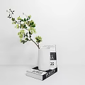 White Ceramic Vase With Small Yellow Flowers Placed On Stack Of Books