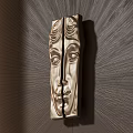 Golden Face Shaped Handle With Detailed Carved Design Mounted On Dark Wall And Radiant Light