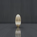 Golden Oval Sculpture with Intricate Cut Out Patterns on Dark Wood Grain Floor and Reflection