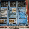 Weathered Blue Entrance Door With Decorative Patterns Striped Panels Bronze Plates And Red Frame