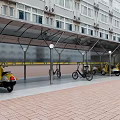 Metal Frame Bicycle Scooter Canopy Near Multi Storey Building with Brick Paved Ground