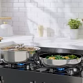 Stainless Steel Cooking Pans On Gas Stove With Blue Flames And Fresh Vegetables