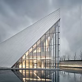 Modern Architectural Building With Triangular Roof Glass Curtain Wall Illuminated Interior And Water Reflection