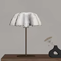 White Petal Shaped Table Lamp With Gold Base On Wooden Table And Black Vase