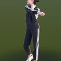 Woman In Black Tracksuit With White Stripes Performing Stretching Against Green Background