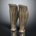 Antique Bronze Greaves With Intricate Carved Patterns On Black Reflective Surface