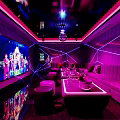 Stylish KTV Lounge Interior With Purple Lighting Large Screen TV Sofas Tables And Decorative Lights