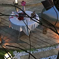 Outdoor Garden Landscape with Wooden Deck Round Table White Tablecloth Sofa Seats Lanterns and Trees