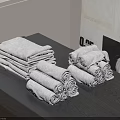 Neatly Stacked Folded And Rolled Towels On Gray Table With Light Wall