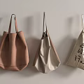 Three Stylish Hanging Bags in Brown and Beige with Text Print on Wall