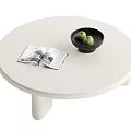 White Round Coffee Table With Open Magazine Black Bowl And Green Fruits