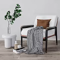 Elegant Armchair With Brown Cushion Checkered Blanket Green Plant And White Stool On Wooden Floor