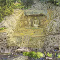 Garden Landscape Featuring Ancient Stone Buddha Statues Cliffside Grottoes And Lush Greenery