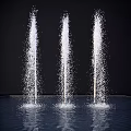 Three Garden Fountains With Spraying Water And Splashing Drops On Dark Background