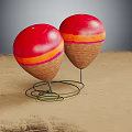 Two Red Spheres With Orange Pink Stripes Brown Bases On Metal Spring Stands On Sand