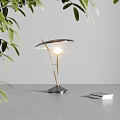 Modern Minimalist Table Lamp With Golden Pole Curved Shade Warm Glowing Light And Green Leaves