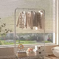 Metal Clothes Rack Holding Light Colored Clothes With Storage Basket And Plant By Window